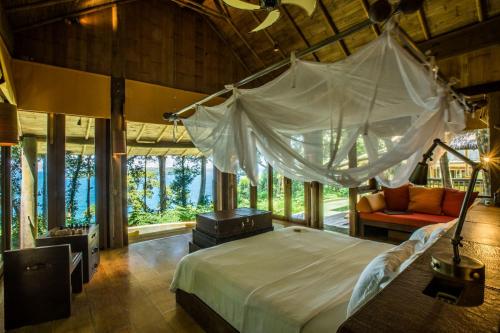 a bedroom with a canopy bed and a couch at Soneva Kiri in Ko Kood