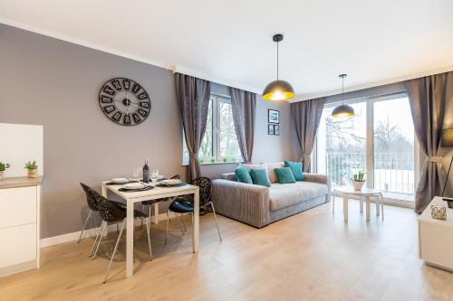 a living room with a couch and a table and a clock at Feniks Apartamenty - Family Club SPA in Kołobrzeg