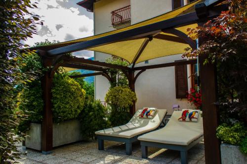 a pergola with two chairs and a bench under it at La casa rosa in Sernio