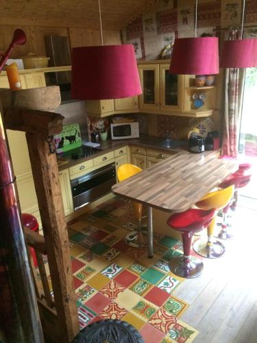 une cuisine avec une table en bois et deux lampes roses dans l'établissement chalet des petits loups, à Chamonix-Mont-Blanc