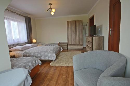 a bedroom with two beds and a couch and a chair at Na Wierchu in Bukowina Tatrzańska