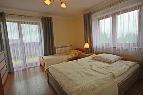 a bedroom with two beds and large windows at Na Wierchu in Bukowina Tatrzańska