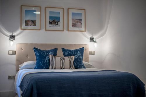 a bedroom with a blue bed with three pictures on the wall at Zurbano in Madrid