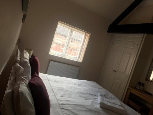 a bedroom with a bed with white sheets and a window at The Atherstone Red Lion Hotel in Atherstone