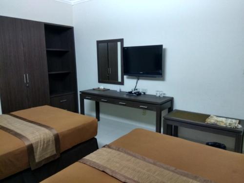 a hotel room with two beds and a flat screen tv at Puri Ratna Joewita in Batusangkar