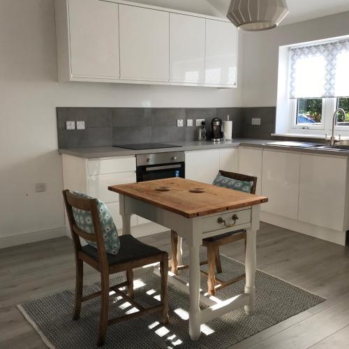 a kitchen with a wooden table and two chairs at Seaglass Cottage, 5 mins from beach, hot tub on request in South Hayling