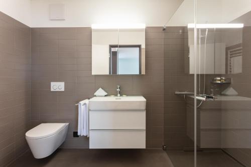 y baño con lavabo, aseo y ducha. en EMA House Serviced Apartments Superior Downtown en Zúrich