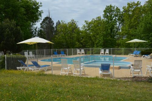 une piscine avec des chaises et des parasols à côté d'une clôture dans l'établissement Camping - Village Vacances Familial à Prayssac au coeur du vignoble Lotois, à Prayssac