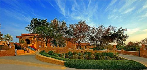 un jardín con arbustos y árboles y un edificio en Hotel Rawalkot Jaisalmer, en Jaisalmer