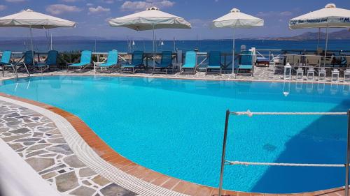 una grande piscina con sedie blu e ombrelloni di Meltemi Studios a Megalochori (Isola di Agistri)