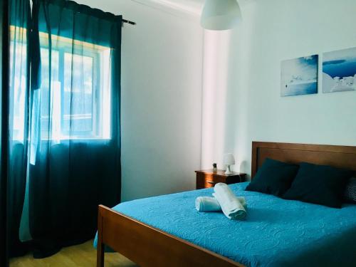 a bedroom with a bed with blue sheets and a window at Apartamento Coselhas Coimbra in Coimbra