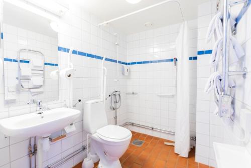 La salle de bains blanche est pourvue de toilettes et d'un lavabo. dans l'établissement Hotell Mörby - Danderyd Hospital, à Danderyd
