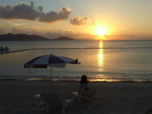 a woman sitting on a beach under an umbrella at Ishigaki Seaside Hotel in Ishigaki Island