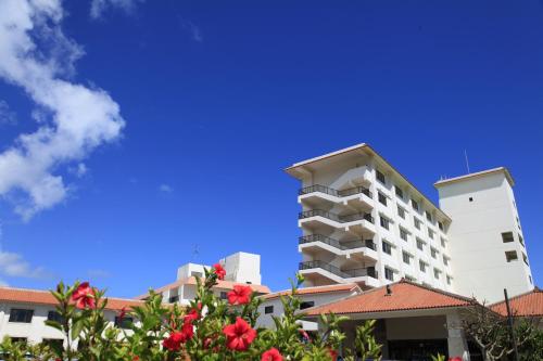 a tall white building with red flowers in front of it at Ishigaki Seaside Hotel in Ishigaki Island