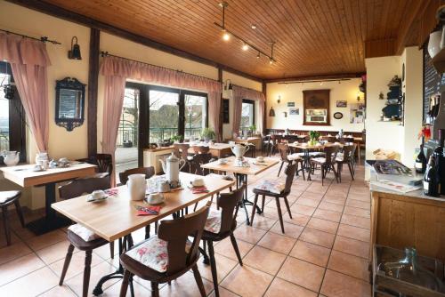 ein Restaurant mit Holztischen, Stühlen und Fenstern in der Unterkunft Restaurant und Gasthaus Zur Burgschänke in Aremberg