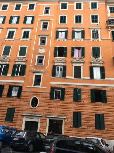 un grande edificio in mattoni arancioni con macchine parcheggiate di fronte di Appartamento - Casa vacanza Nonna Grazia a Roma