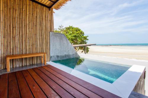 een zwembad op een houten terras naast een strand bij The Humble Villas in Ban Bang Po