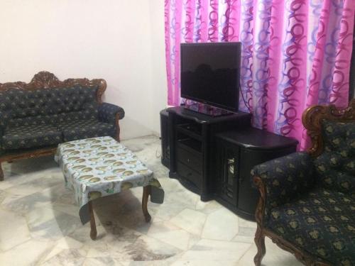 a living room with two chairs and a tv at Homestay PD in Port Dickson