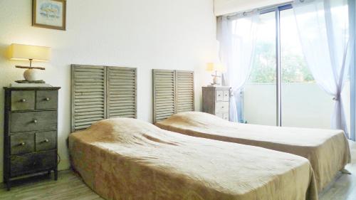 a bedroom with two beds and a dresser and a window at B13 Appartement avec Parking proche Plage in Arcachon