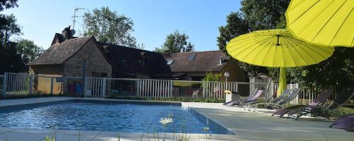 ロカマドゥールにあるVillage de Chalets de Rocamadourの家の隣に椅子とパラソル付きのプールがあります。