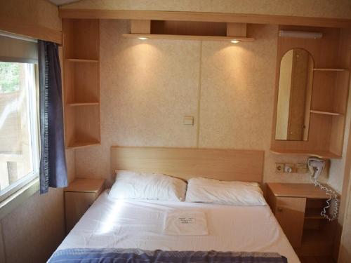 - une petite chambre avec un lit et un miroir dans l'établissement Village de Chalets de Rocamadour, à Rocamadour