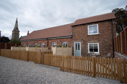 a brick house with a wooden fence and a church at Carlton Towers Stapleton's & Parkgate's in Carlton