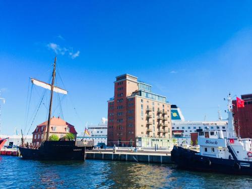 two boats docked at a dock with a tall building at Am Hafen - Ohlerichspeicher in Wismar