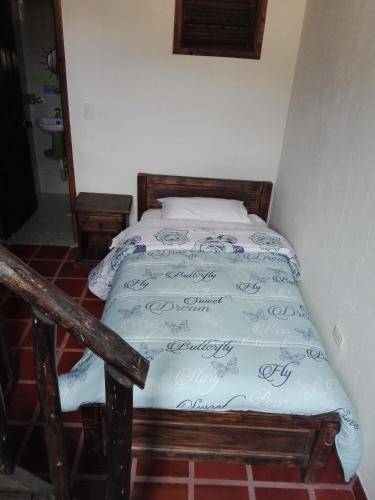 a small bed in a room with a bedspread at Spa Posada 4 Esquinas in La Uvita
