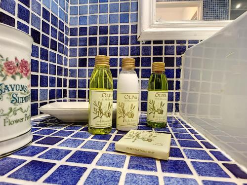 3 bouteilles de vin sur un comptoir de salle de bains en carrelage bleu dans l'établissement Nestor&Jeeves - CARDELINE TERRASSE - Very close sea - Spacious, à Nice