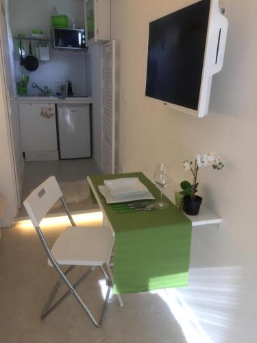 a green table with a chair and a television on a wall at Privatzeit The green Mile in Leverkusen