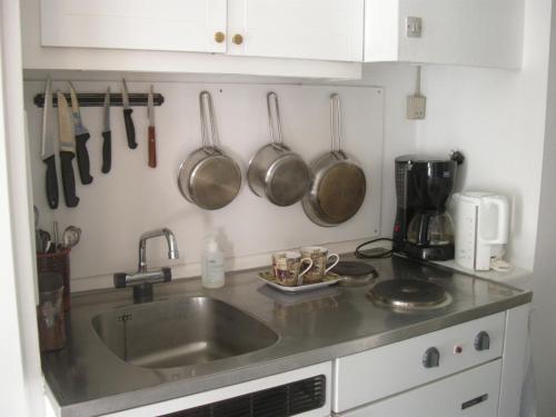 a kitchen with a sink and pots and pans on the wall at Mini-apartment in the flowerbed in Søborg