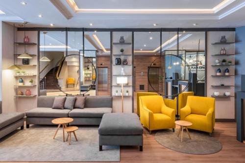 a living room with a couch and yellow chairs at Hotel Madrid Plaza de España, Affiliated by Meliá in Madrid