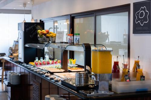 a buffet line with food and drinks on a counter at Hotel Madrid Plaza de España, Affiliated by Meliá in Madrid