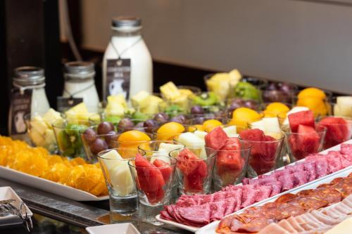 a buffet filled with different types of fruit in cups at Hotel Madrid Plaza de España, Affiliated by Meliá in Madrid