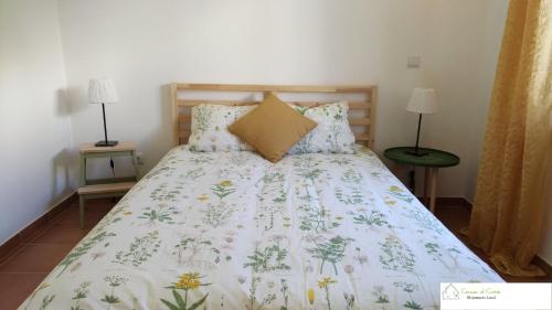 a bed with a white comforter with flowers on it at Casa D'Avó (R/C) in Altura