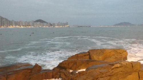 a beach with rocks and the ocean and buildings at Pousada Brilho do Sol in Guarujá