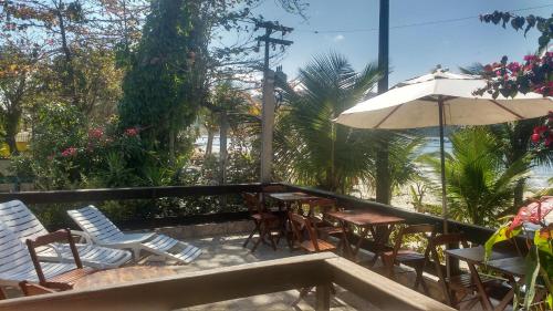 a patio with chairs and tables and an umbrella at Pousada Brilho do Sol in Guarujá