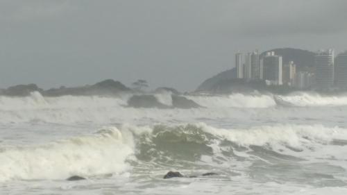 a wave in the ocean with a city in the background at Pousada Brilho do Sol in Guarujá