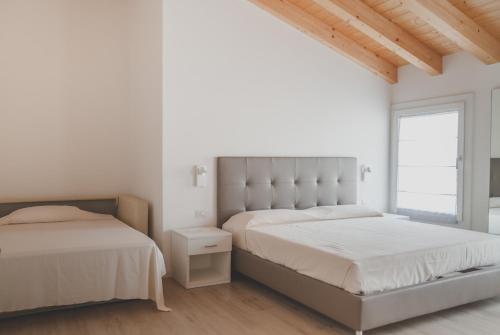 two beds in a bedroom with white walls and wooden ceilings at Terra Ferma Rooms&More in Salzano
