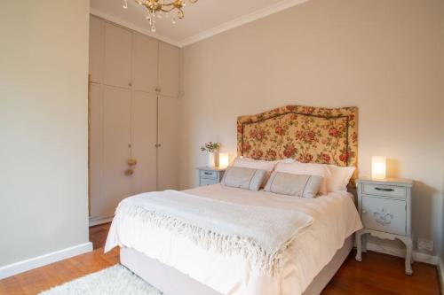 1 Schlafzimmer mit einem weißen Bett mit einem floralen Kopfteil in der Unterkunft 11 Deerpark Drive East in Kapstadt