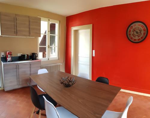 a dining room with a wooden table and a red wall at Manoir du Chambellan in Arnières-sur-Iton
