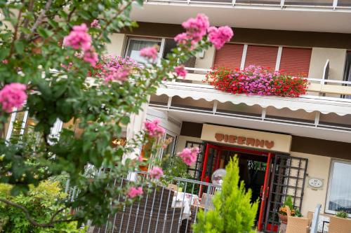 an old man sitting in the window of a building with pink flowers at Hotel Tiffany in Merano