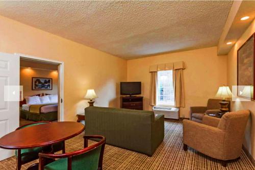 a hotel room with a bed and a living room at Baymont by Wyndham Columbia Maury in Columbia