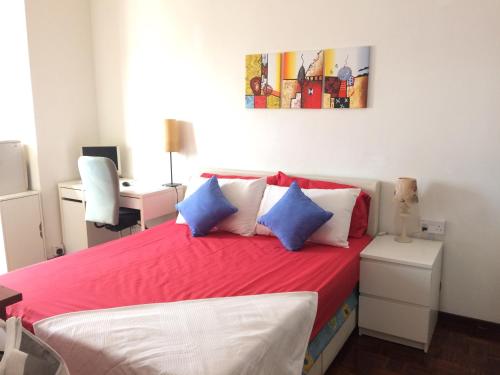 Un dormitorio con una cama roja con almohadas azules y blancas en Suria Kipark Damansara 750sq ft Studio Apartment, en Kepong