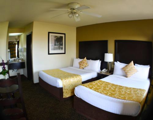 a hotel room with two beds and a ceiling fan at Hotel America in Tijuana