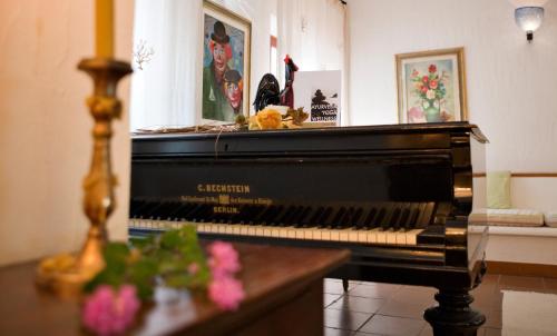 a piano sitting in a living room with flowers at Hotel Gallo Nero in SantʼAndrea