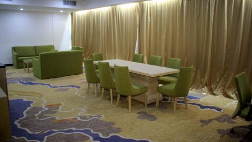 a conference room with a table and green chairs at Melian Hotel in An Najaf