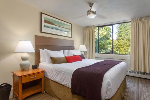 ein Schlafzimmer mit einem Bett und einem großen Fenster in der Unterkunft West Coast Suites at UBC in Vancouver