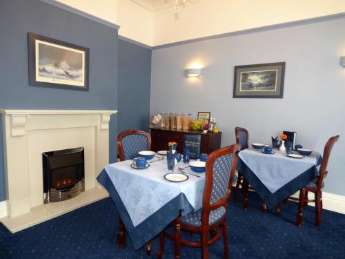 a dining room with two tables and a fireplace at Whitehaven Guest House in Whitby