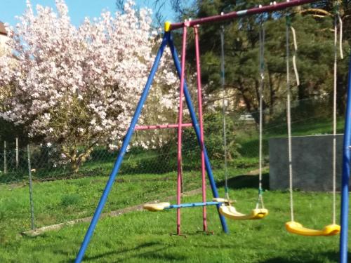a playground with swings in a yard with flowers at la maison seillere in Senones
